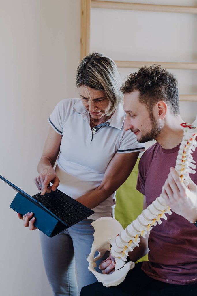 Physiotherapeutin zeigt einem Patienten etwas auf dem Tablet