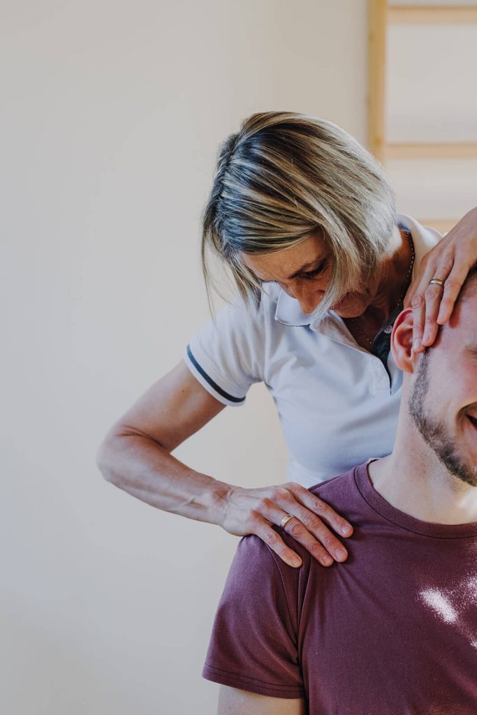 Physiotherapeutin behandelt Patient am Nacken