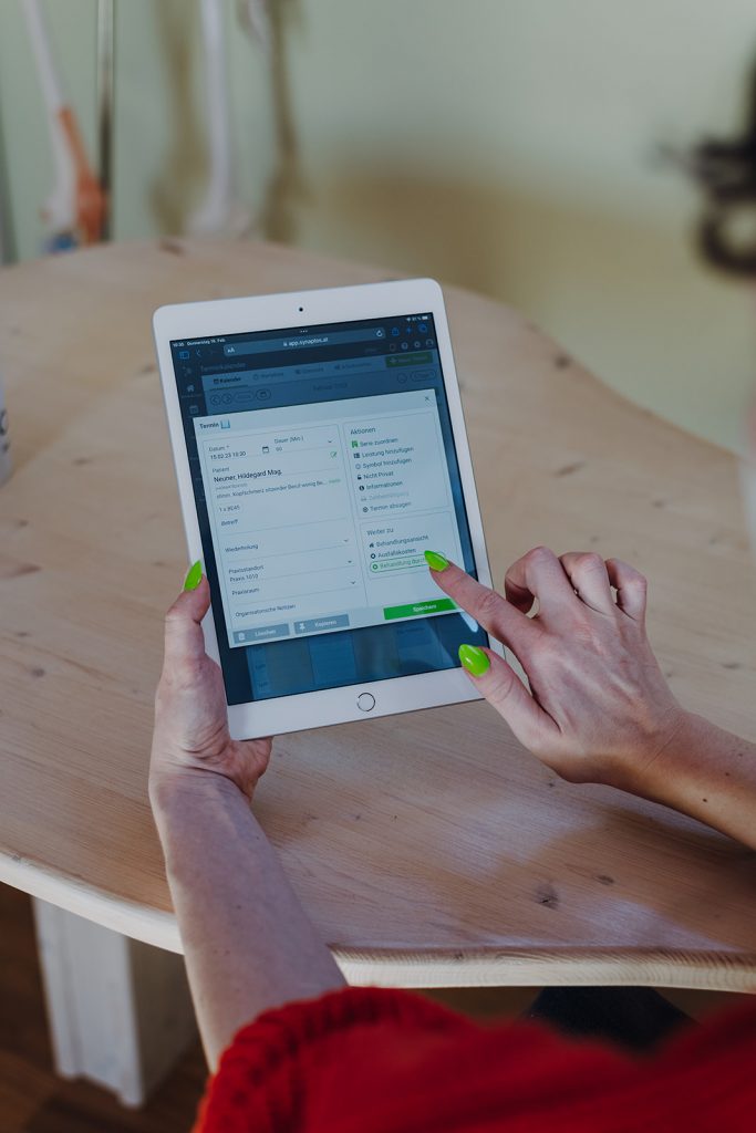 Frau mit orangem Pullover tippt auf weißem Tablet