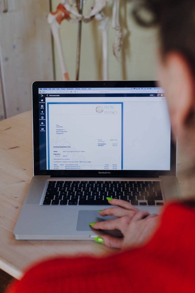 Frau mit orangem Pullover und grünen Nägeln erstellt auf MacBook Pro Honorarnote