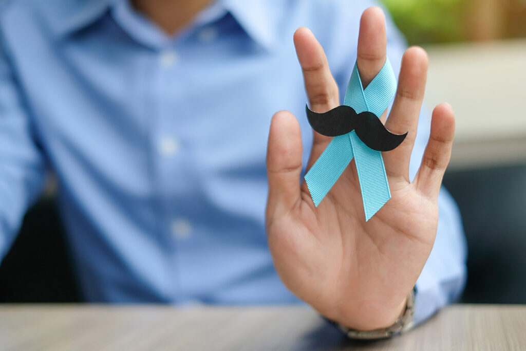 mann hält blaueschleife mit schnurrbart für movember